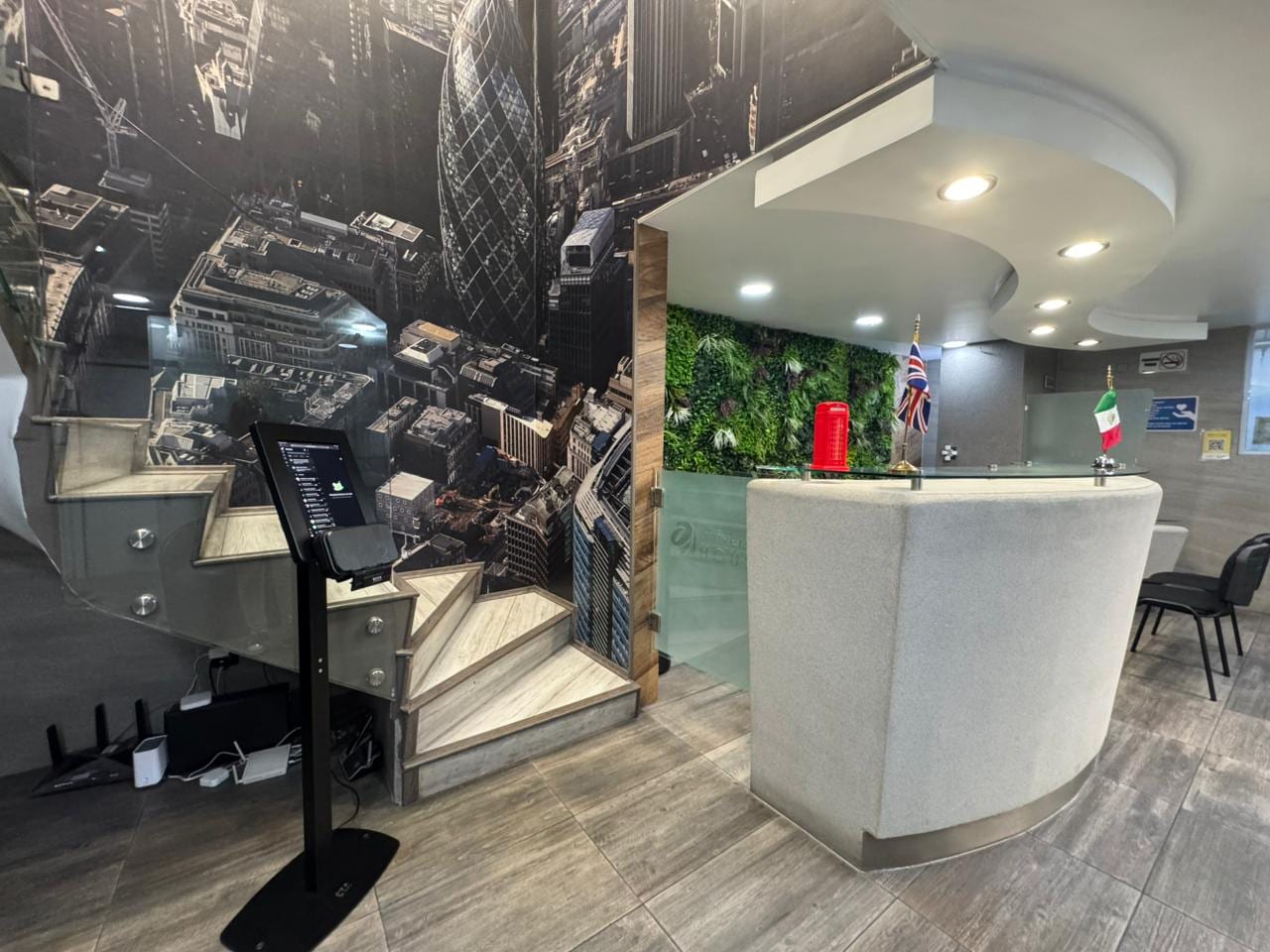 Recepción Universal House con mural panorámico de Londres, escalera y barra blanca curva
